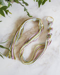 Multicolored braided macrame plant hanger on a marble surface with green leaves at Paisley Gardens in Northfield, MN.