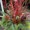 A festive holiday  arrangement featuring green pine needles, brown magnolia leaves, pink eucalyptus, bright red berries and red dogwood stems at Paisley Gardens in Northfield, MN.