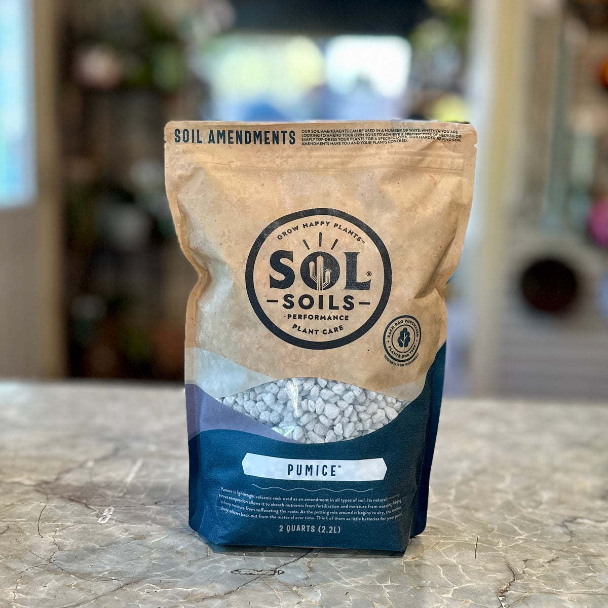 A 2 quart bag of Sol Soils Pumice soil amendments is standing on a marble countertop with a blurred indoor background at Paisley Gardens in Northfield, MN.