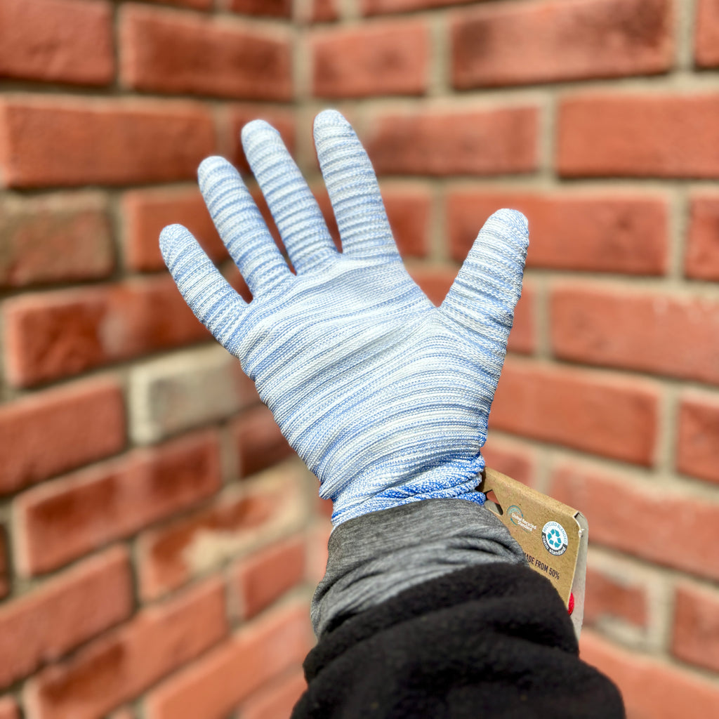 The palm of a person modeling a bluish white gardening glove in front of a blurred brick background at Paisley Gardens in Northfield, MN.